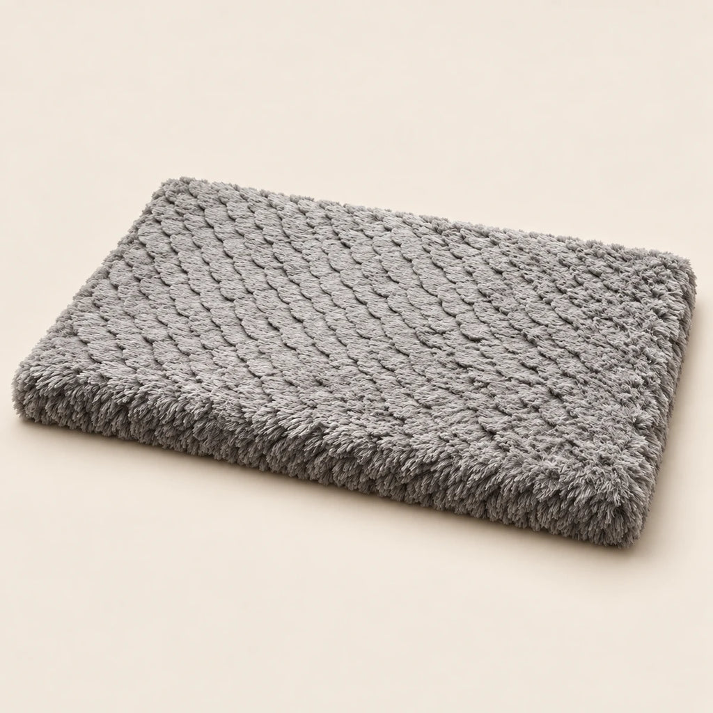 Flat rectangular grey plush dog mat on a sand-coloured background