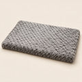 Flat rectangular grey plush dog mat on a sand-coloured background