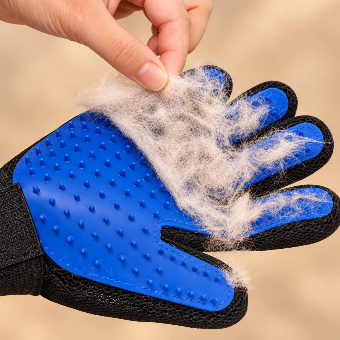 Blue grooming glove with loose pet hair gathered on the silicone pins