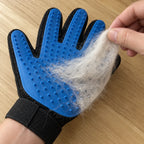Hand pulling a clump of loose pet fur off the blue silicone glove